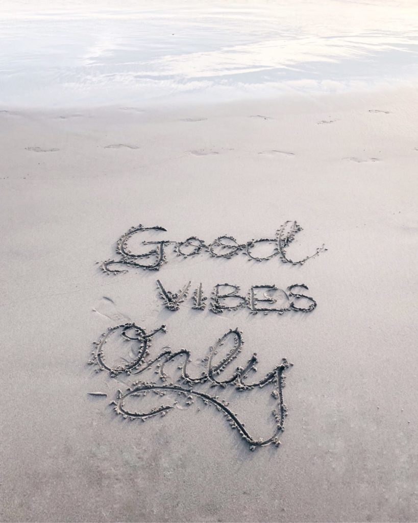 good vibes written in sand on the beach
